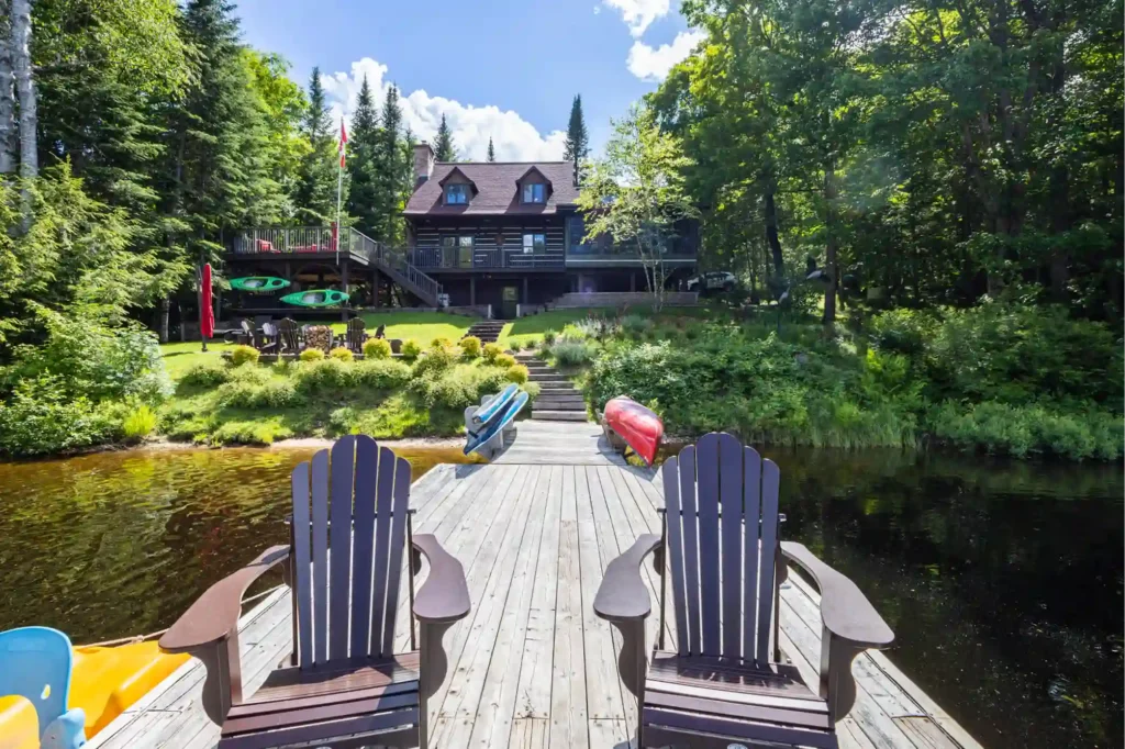 Muskoka lakefront cottage with private dock, Muskoka chairs, kayaks, canoe, and Canadian flag representing the real cottage country inspiration behind Sterling Point on Prime Video