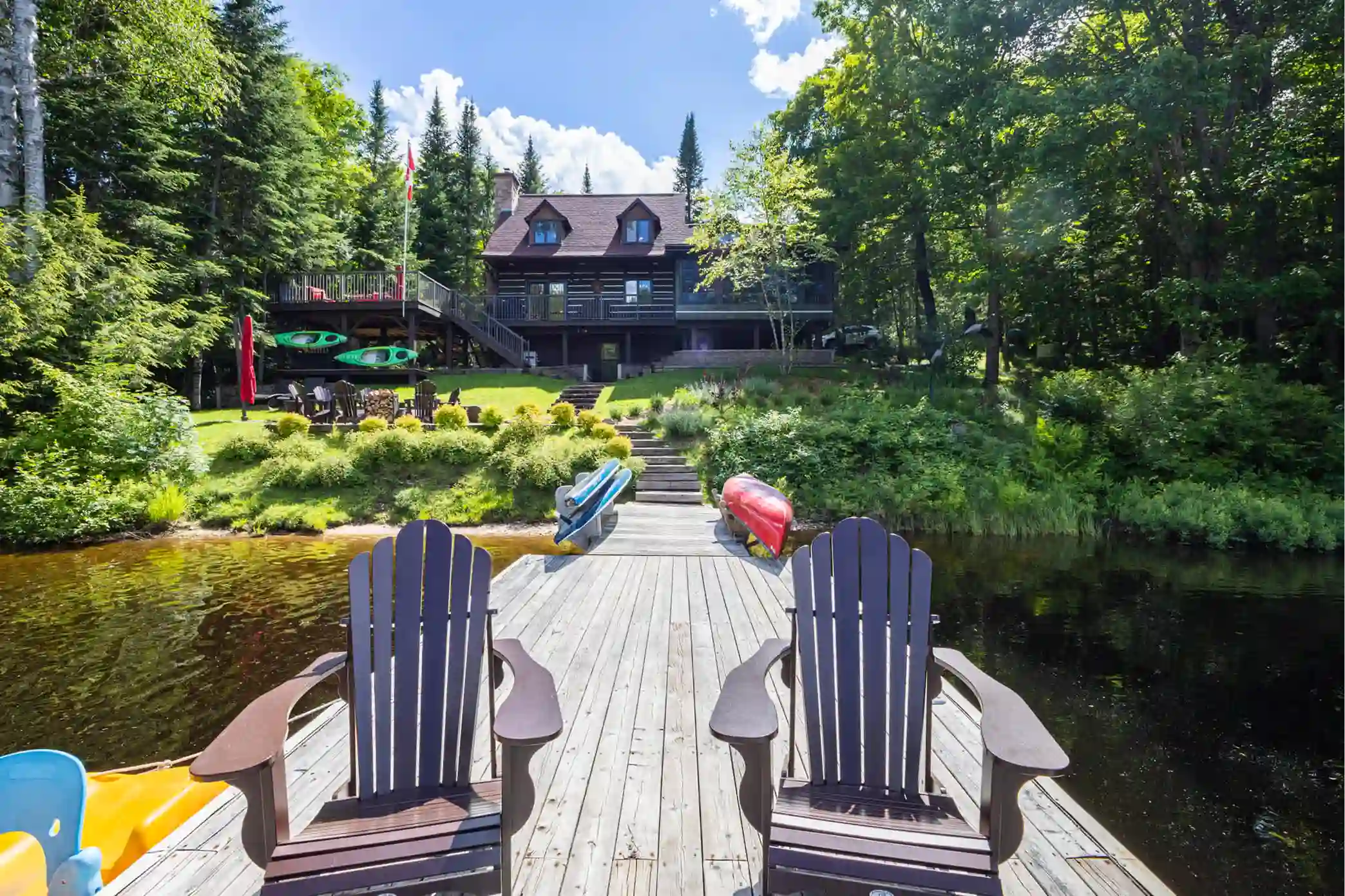 Muskoka lakefront cottage with private dock, Muskoka chairs, kayaks, canoe, and Canadian flag representing the real cottage country inspiration behind Sterling Point on Prime Video