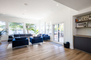 Modern minimalist cottage living room with navy blue sofas and large lakefront windows