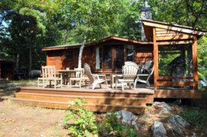 Rustic wood cottage with spacious deck and outdoor seating among trees